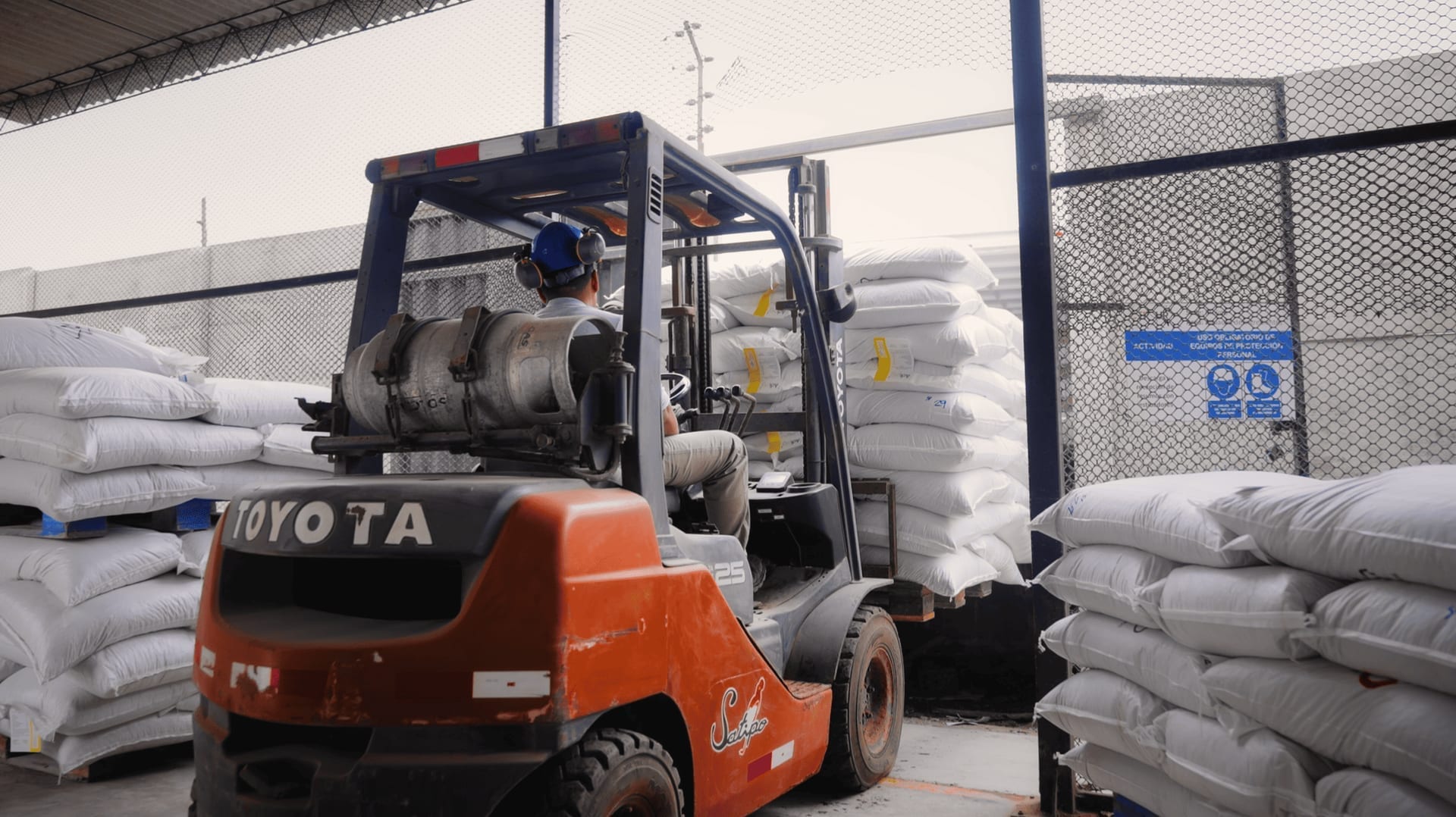 Minicargador moviendo sacos de alimento terminado en planta Molinos CERSUR — almacenamiento y despacho.